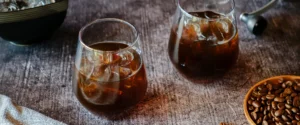 Cold Brew Kaffee: zwei Gläser mit Cold Brew und Eiswürfeln, daneben Kaffeebohnen