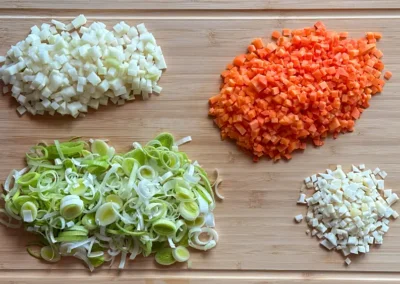 Das geschnittene Gemüse für die Eierstichsuppe auf einem Schneidbrett