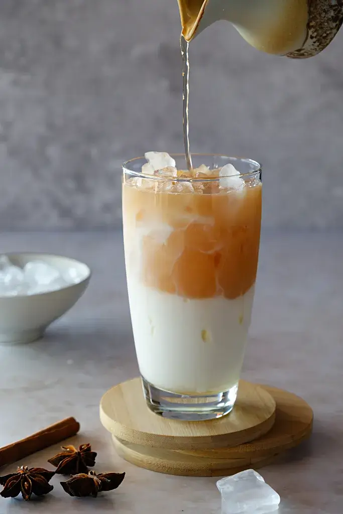 Marmorierung und Schichten beim Einschenken des Chai Iced Chai Latte im Glas beim Einschenken des Chai-Tees