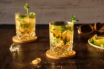 Alkoholfreier Mojito, dekoriert mit Minze, Limetten daneben und mit Rohrzucker im Vordergrund