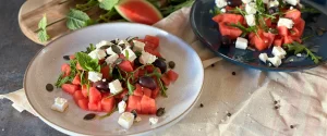 Wassermelonen-Feta-Salat mit Rucola auf Tellern angerichtet